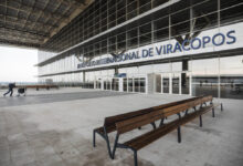 A imagem mostra a fachada do Aeroporto Internacional de Viracopos, com um grande letreiro em letras azuis que diz