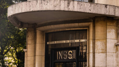 A imagem mostra a fachada de um edifício que abriga o INSS (Instituto Nacional do Seguro Social). A entrada é marcada por uma porta de ferro com a sigla