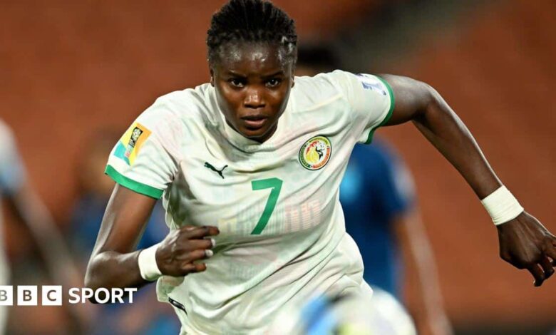 Mama Diop, wearing a white Senegal shirt, chases after the ball